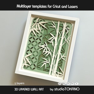 May include: A white framed 3D layered wall art piece featuring a bamboo forest design with five distinct layers. The artwork displays white bamboo stalks and leaves over a green background with a circular geometric pattern. Text reads Multilayer templates for Cricut and Lasers, 5 layers, 3D LAYERED WALL ART, and studioTOKANO.