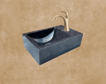 May include: A black rectangular vessel sink with a gold faucet. The sink is made of natural stone and has a smooth, polished finish.
