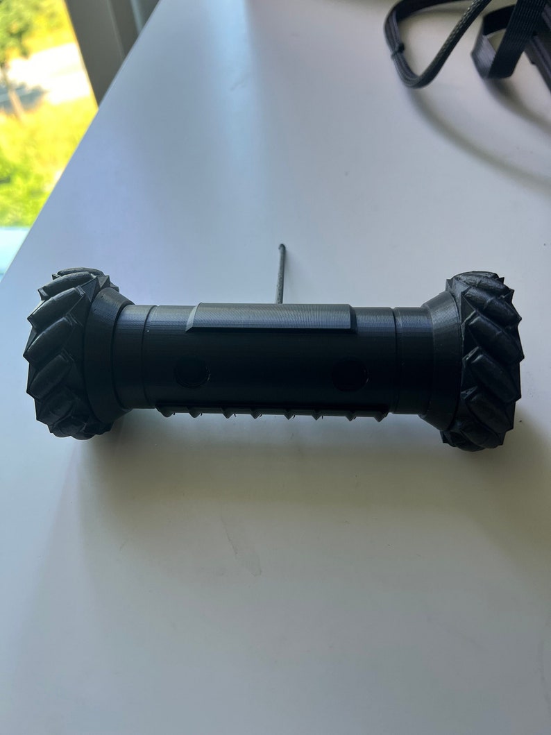 May include: A black, 3D printed robot with a textured wheel at each end. The robot has a small antenna on top.