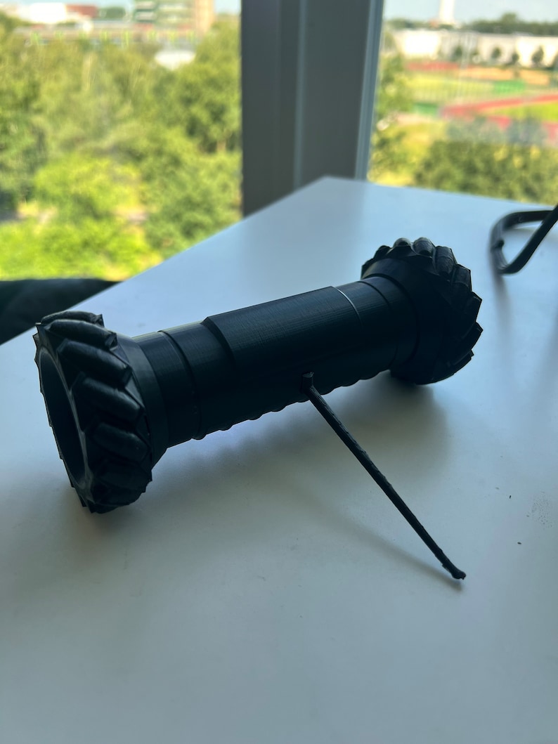 May include: A black 3D printed gear with a thin black string attached to it.