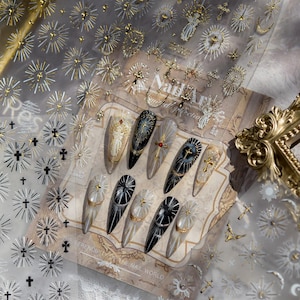 Könnte beinhalten: Nagelkunst-Aufkleber mit goldenen und silbernen Kreuzen, Sonnenstrahlen und Engelmotiven. Enthält ein Blatt dekorierter Acrylnägel mit religiösem Kunstmotiv. Der Text "Nail Art Collection" ist sichtbar.