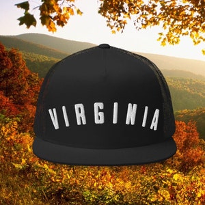 May include: Black mesh trucker hat with a white embroidered "VIRGINIA" logo. The hat is photographed against a backdrop of fall foliage.