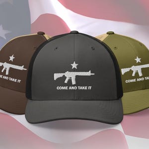May include: Three baseball caps in brown, black, and olive green, each featuring a white graphic of a rifle and a star, with the text "COME AND TAKE IT." The caps have a mesh back and a curved brim.