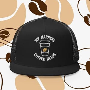 Puede incluir: Gorra de camionero negra con un diseño bordado en blanco que dice "Sip Happens Coffee Helps" y una taza de café con un grano de café dentro.
