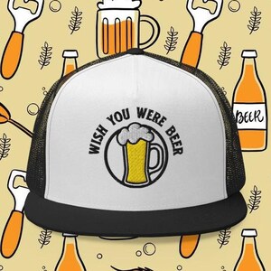May include: White and black trucker hat with a black mesh back. The front of the hat has an embroidered design of a beer mug with the text "Wish You Were Beer".