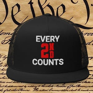 以下が含まれることがあります： 「EVERY 2ND COUNTS」の文字が白と赤でプリントされた黒いトラッカーハット。メッシュバックとカーブしたつばが特徴です。背景にはアメリカ合衆国憲法の一部が写っています。