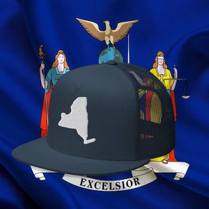 May include: A dark blue and black mesh baseball cap with a white outline of the state of New York on the front. The cap is on top of the New York state flag, which features a blue background with a coat of arms in the center. The coat of arms includes a woman holding a staff, a woman holding a scale, and an eagle with its wings spread.