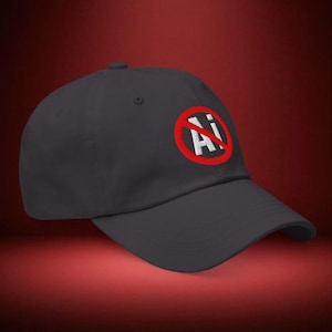 May include: A dark gray baseball cap featuring an embroidered design on the front. The design consists of a red circular border with a diagonal red line crossing through it, surrounding the white text Ai in a bold, sans-serif font style.
