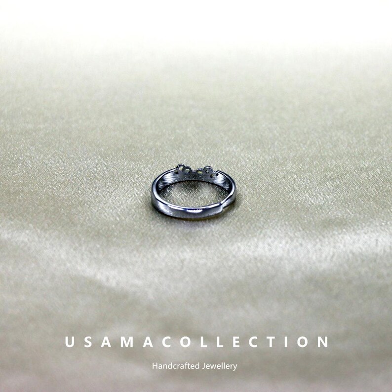 May include: A silver-colored ring with a floral design. The ring is set against a neutral background. The text "USAMA COLLECTION" and "Handcrafted Jewellery" are at the bottom of the image.