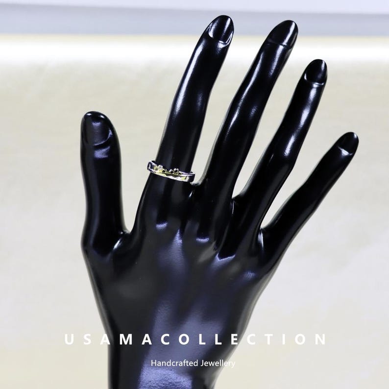 May include: A silver ring with a gold-colored design is displayed on a black hand. The ring features a delicate, possibly floral, pattern. The image also includes the text "USAMA COLLECTION Handcrafted Jewellery."