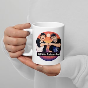 May include: White ceramic mug featuring a colorful illustration of two men fist-bumping against a sunset backdrop. The mug has the text "Hollywood Producers React" in a black rectangle.