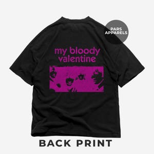 以下が含まれることがあります： バンド「マイ・ブラッディ・バレンタイン」のメンバーの顔がピンクのグラフィックプリントされた黒いTシャツ。