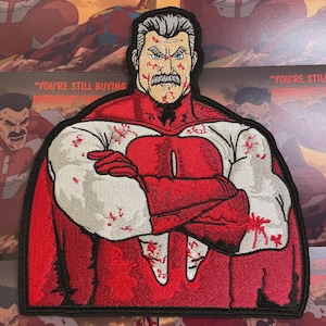 May include: Embroidered patch featuring a stern-faced character in a red and white costume with a black border. The character has a gray mustache and is covered in red blood-like splatters. The text "YOU'RE STILL BUYING PATCHES?? THOUGH" is visible.