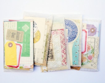 May include: A collection of five translucent glassine envelopes filled with assorted paper ephemera, including vintage-style tickets labeled ADMIT ONE, colorful tags, floral patterns, grid paper, and circular decorative cutouts.