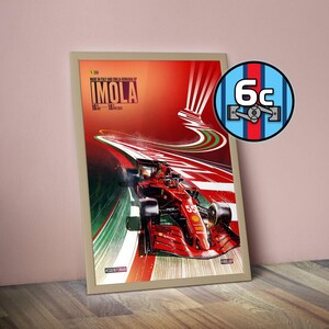 May include: Framed poster depicting a red Formula 1 car racing on a track. The poster has a red and white background with the word "IMOLA" and the dates "16-18 Apr 2021". A circular logo with the number "6c" is in the upper right corner.