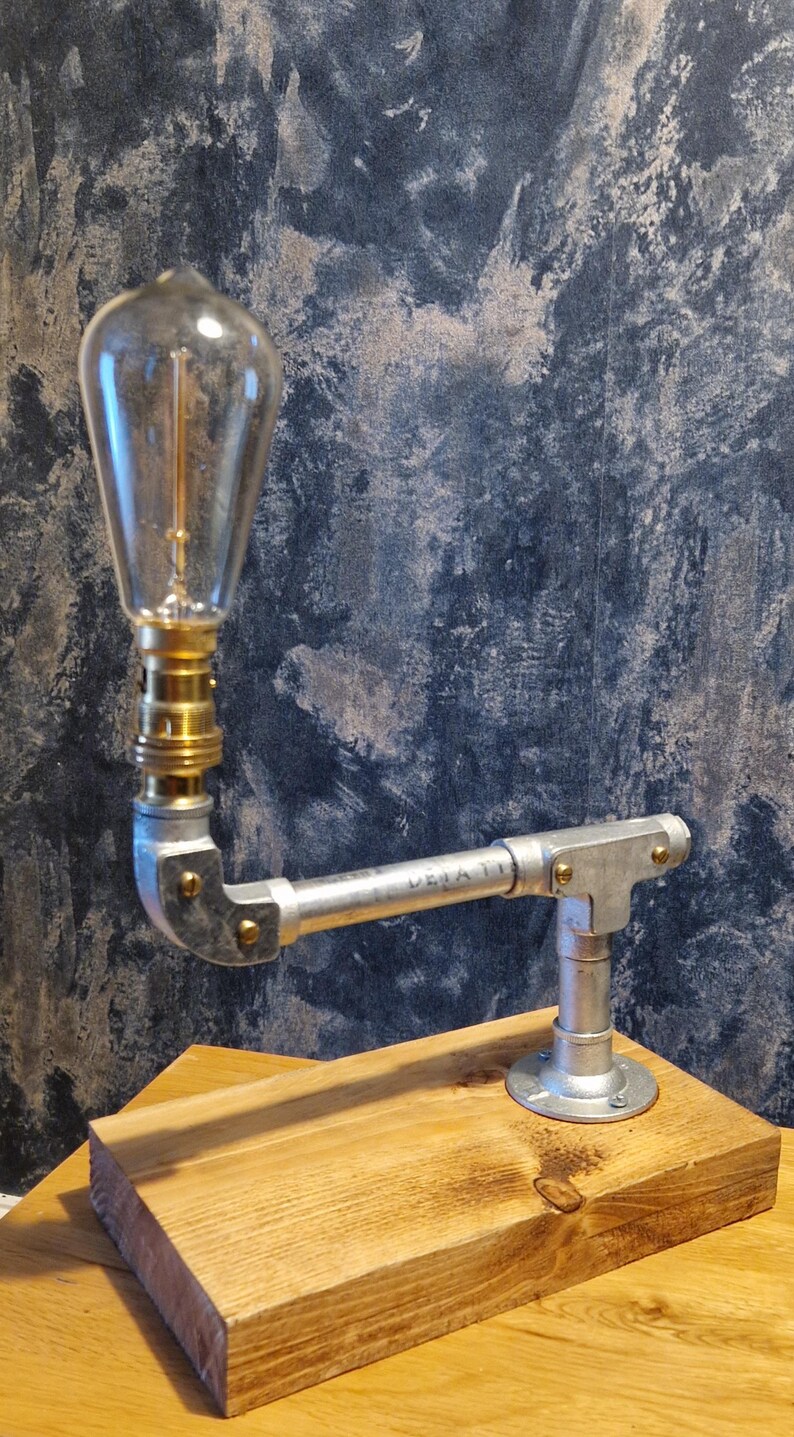 A modern industrial steampunk decor style desk lamp made from galvanized steel pipe and a wooden base.