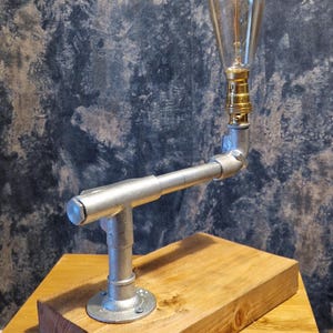 A modern industrial steampunk decor style desk lamp made from galvanized steel pipe and a wooden base.