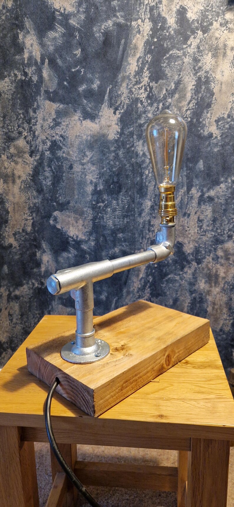 A modern industrial steampunk decor style desk lamp made from galvanized steel pipe and a wooden base.