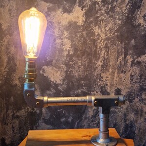 A modern desk lamp made from galvanized steel pipe and a wooden base.