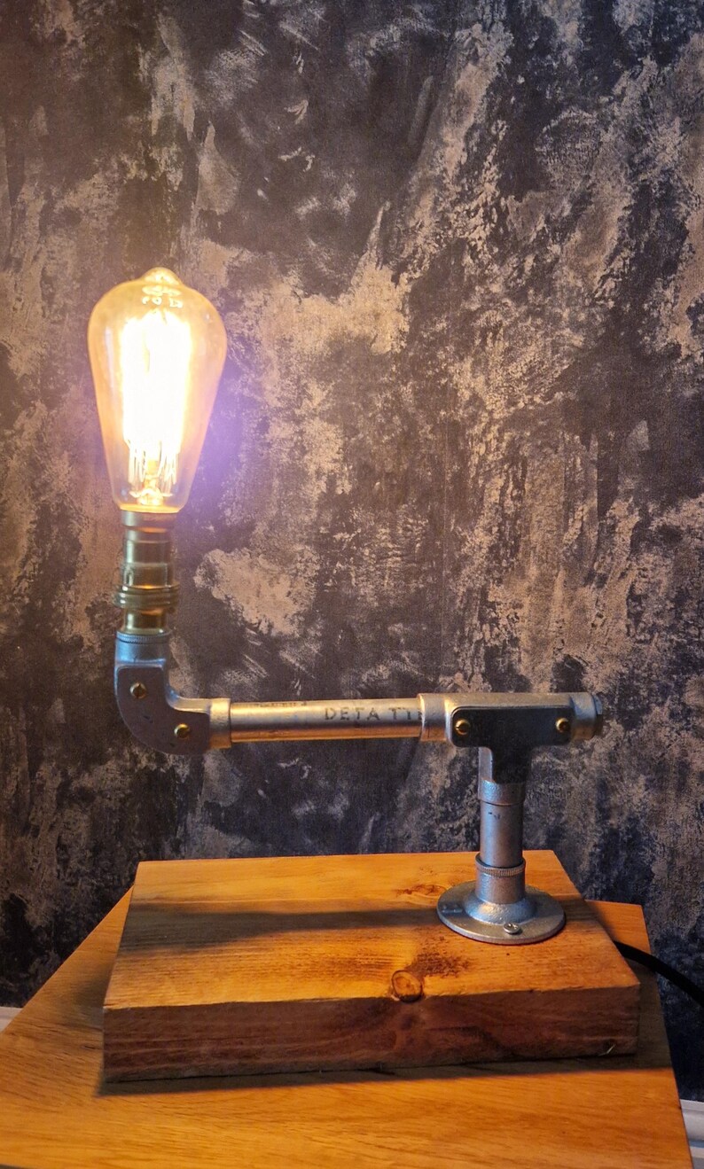 A modern desk lamp made from galvanized steel pipe and a wooden base.