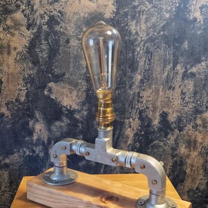 A modern desk lamp made from galvanized steel pipe and a wooden base.