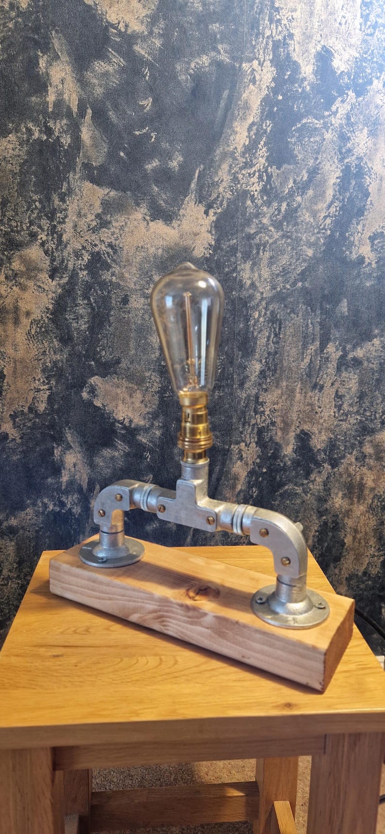 A modern desk lamp made from galvanized steel pipe and a wooden base.
