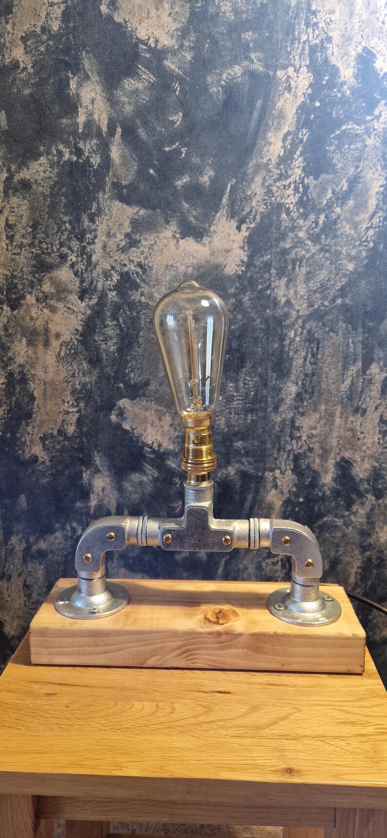 A modern industrial steampunk decor style desk lamp made from galvanized steel pipe and a wooden base.