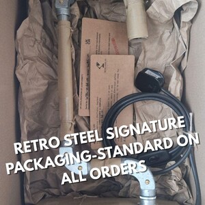 May include: A retro steel product is packaged in a cardboard box with brown paper and twine. The product is wrapped in brown paper. The text "RETRO STEEL SIGNATURE PACKAGING-STANDARD ON ALL ORDERS" is visible.