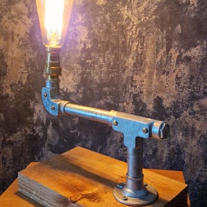 A modern desk lamp made from galvanized steel pipe and a wooden base.
