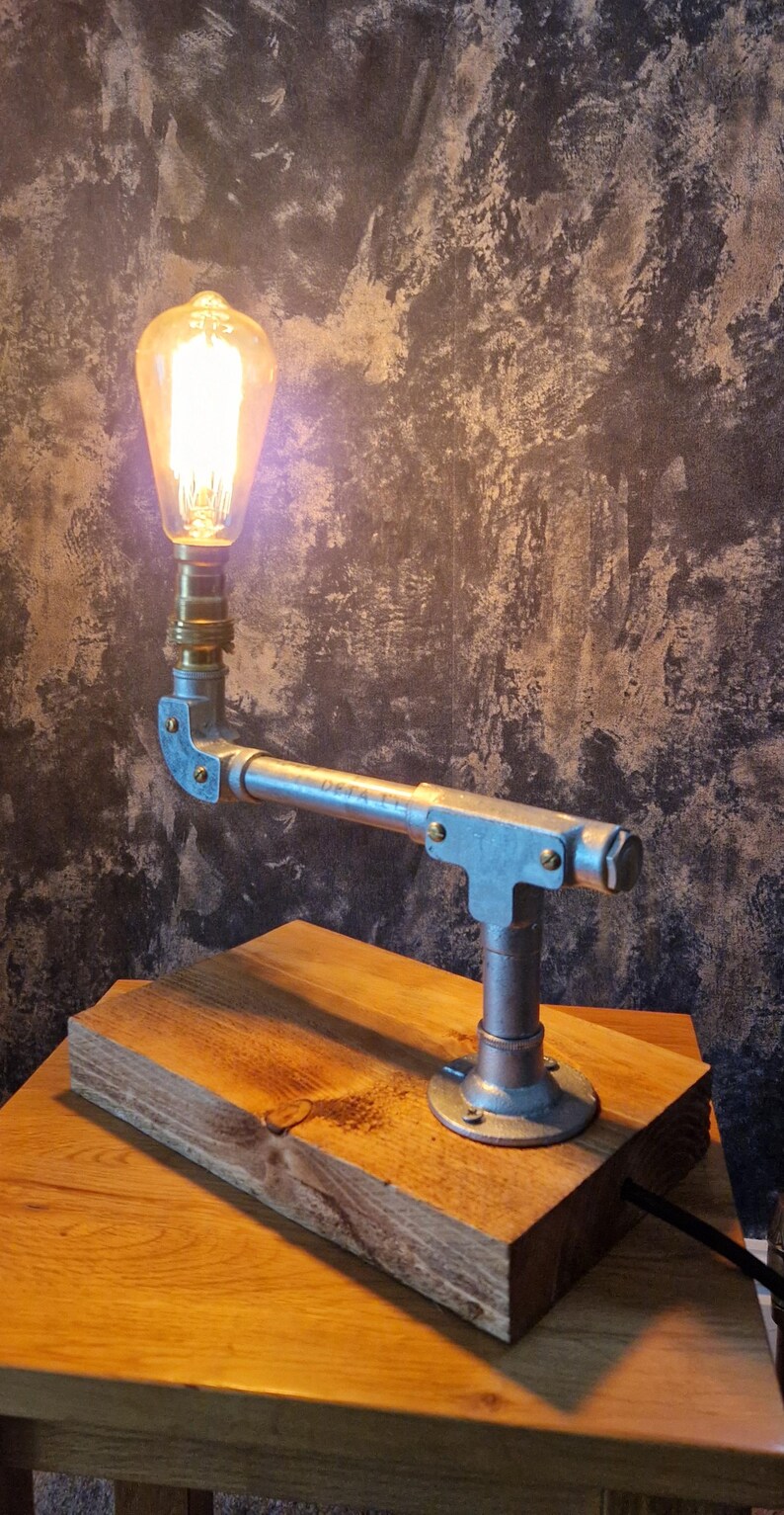 A modern desk lamp made from galvanized steel pipe and a wooden base.