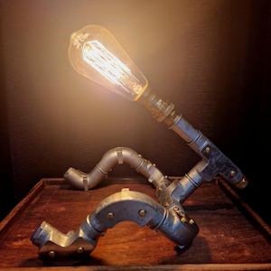 Side profile of a pipe man desk lamp showing the professional industrial wiring and sturdy steel joints.