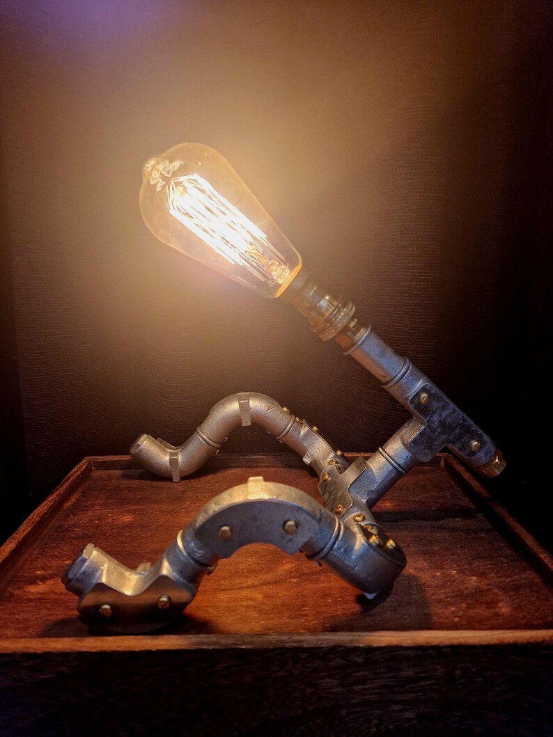 Side profile of a pipe man desk lamp showing the professional industrial wiring and sturdy steel joints.