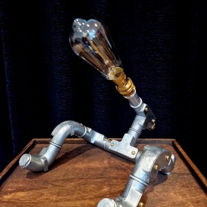 Steampunk Pipe light made from galvanised conduit in a Pipe Man robot sClose-up of a vintage LED filament bulb in a silver steel pipe fixture handcrafted in Sheffield.