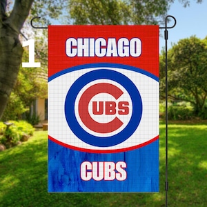 May include: A Chicago Cubs garden flag. The flag features the team's logo, a blue and red circle with the letters "UBS" inside, set against a white grid. The words "CHICAGO" and "CUBS" are displayed in white on a red and blue background.