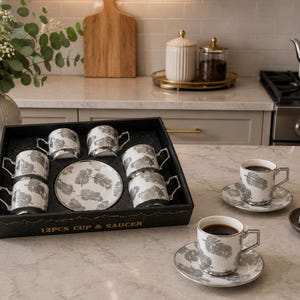 Peut inclure: Un service à café de 12 pièces avec des tasses et des soucoupes à motif de plumes. Les tasses et les soucoupes blanches présentent un motif de plumes grises et des bordures argentées. L'ensemble est présenté dans un plateau noir.