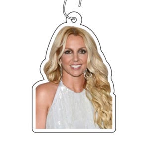 May include: A close-up portrait of a woman with long blonde hair wearing a white sequined halter top.