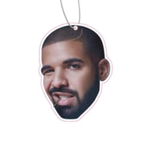 May include: A black and white photo of a man's face with a beard and a slight smirk. The photo is printed on a white car air freshener.