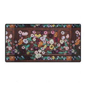 May include: A rectangular desk mat featuring a dark brown wooden panel design with colorful floral accents. The flowers include pink, white, yellow, orange, and purple blooms with green leaves. The mat has a black border.