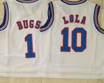 May include: Two white basketball jerseys with blue and red trim. The jersey on the left has "BUGS" and the number "1" on the back. The jersey on the right has "LOLA" and the number "10" on the back.