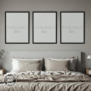 May include: Bedroom interior with a bed, nightstands, and three framed art pieces. The frames are black, and the art pieces have the text "YOUR DESIGN here". The bed has beige bedding and pillows. A lamp and clock are on the nightstand.