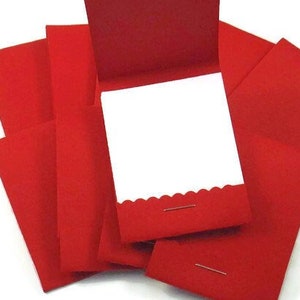 May include: A stack of red envelopes with scalloped edges and a white card inside. The envelopes are held together with a metal pin.