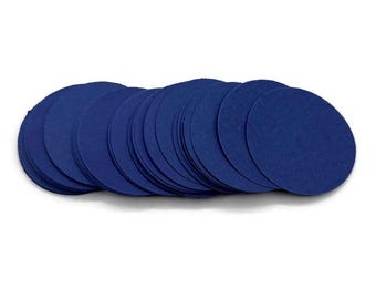 May include: A stack of navy blue circular paper coasters. The coasters are arranged in a slightly fanned-out pattern, showcasing their uniform shape and color. The image is shot against a plain white background.