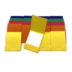 May include: A set of 10 colorful mini notebooks with yellow covers and white paper. The notebooks are folded in half and have a scalloped edge. They are arranged in a row on a white surface.