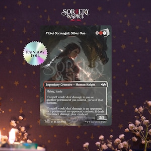 May include: A Magic: The Gathering card featuring Violet Sorrengail, Silver One. The card has a woman with a dragon in the background. The card is a Legendary Creature - Human Knight with Flying and Haste abilities. A rainbow foil sticker is on the left.