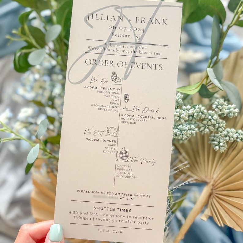 Op de afbeelding: Een trouwkaart met de namen "Jillian + Frank" en de datum "06.07.2024" bovenaan afgedrukt. De kaart geeft de details van de ceremonie, het diner en het feest weer. De kaart wordt vastgehouden door een persoon met een lichtblauwe manicure.