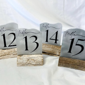 May include: Four gray table number signs with black text on wooden bases. The signs read "table 12", "table 13", "table 14", and "table 15".