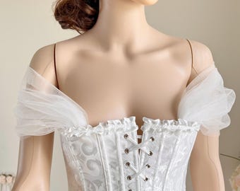 May include: White off-the-shoulder corset with a lace-up back and a white tulle overlay on the shoulders.