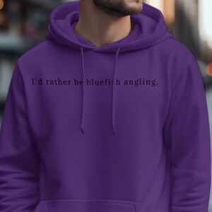 May include: A purple hoodie with the text "I'd rather be bluefish angling." printed on the front.