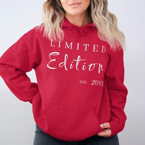 Könnte beinhalten: Ein roter Kapuzenpullover mit einer Vordertasche und einer Kapuze mit Kordelzug. Der Kapuzenpullover trägt die Worte "LIMITED Edition" in weißer Schrift, darunter "EST. 2003". Der Kapuzenpullover ist aus einem weichen Material.