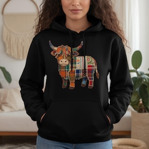 Op de afbeelding: Zwarte hoodie met een Highland koeien ontwerp. De koe is afgebeeld in patchwork-stijl, met behulp van verschillende geruite en bloemmotieven in oranje, groen, rood en blauw. De hoodie heeft een capuchon met trekkoord en een voorzak.